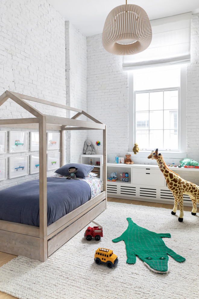Modern inredning av ett stort barnrum kombinerat med sovrum, med vita väggar, ljust trägolv och brunt golv