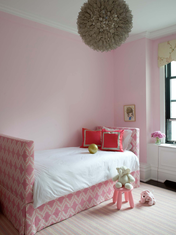 Trendy girl dark wood floor and brown floor kids' room photo in New York with pink walls