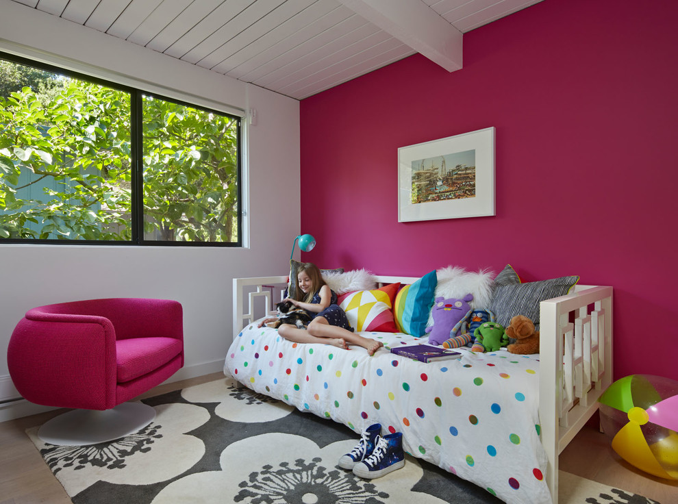 Imagen de dormitorio infantil retro con suelo de madera clara y paredes multicolor