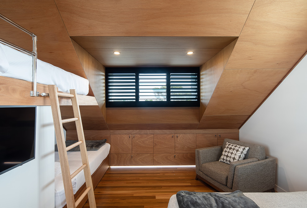 Réalisation d'une chambre d'enfant marine avec un mur blanc, un sol en bois brun, un sol marron et un lit superposé.