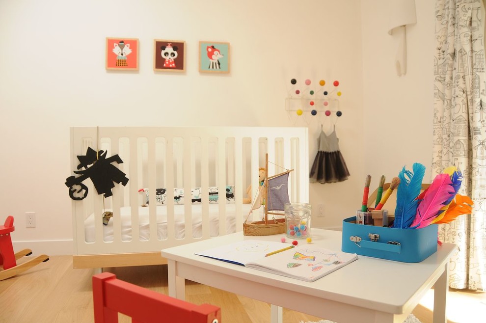 Toddler room - contemporary gender-neutral light wood floor toddler room idea in Los Angeles with white walls