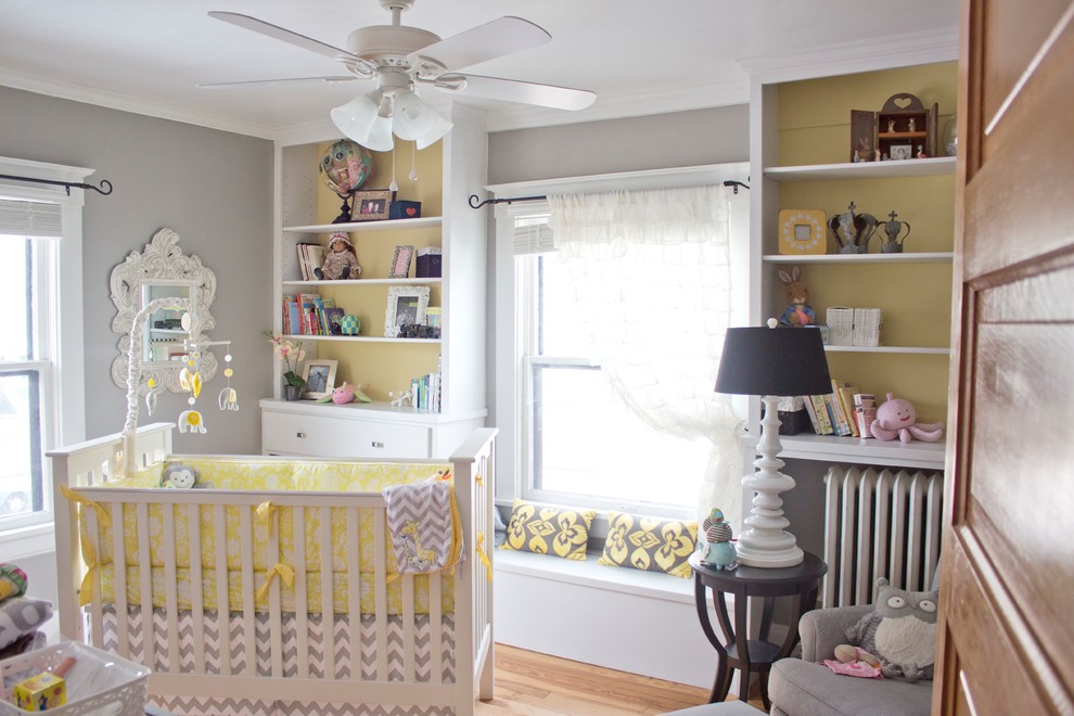 This is an example of a small classic gender neutral toddler’s room in Other with grey walls and medium hardwood flooring.