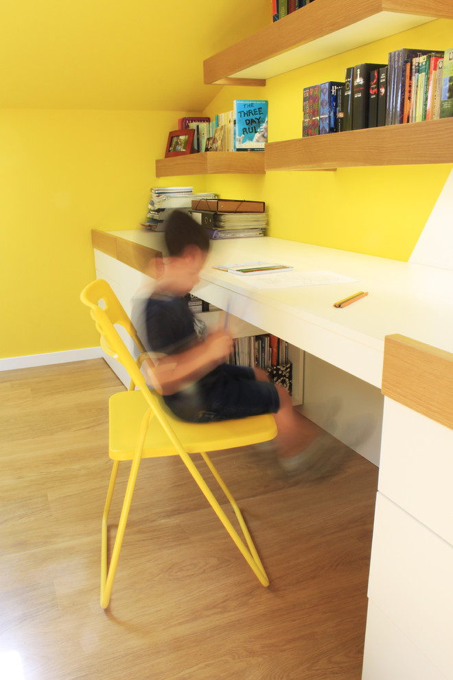 Foto de habitación infantil unisex de 4 a 10 años contemporánea de tamaño medio con escritorio, paredes amarillas y suelo de madera en tonos medios
