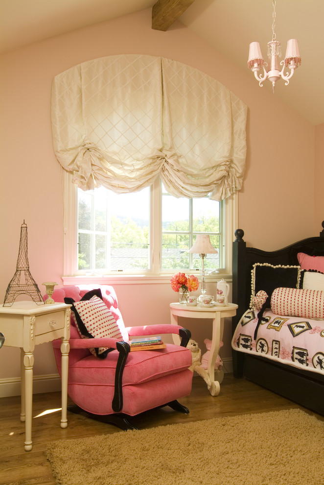Diseño de habitación de bebé niña abovedada clásica pequeña con paredes rosas, suelo de madera clara y suelo beige