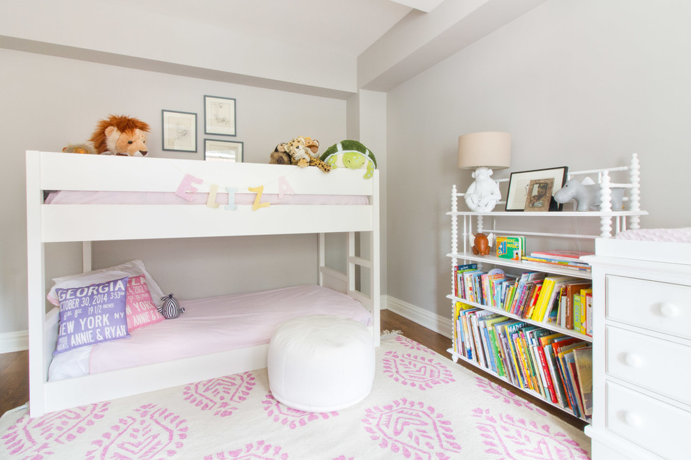 Photo of a classic toddler’s room for girls in New York with grey walls, medium hardwood flooring and brown floors.