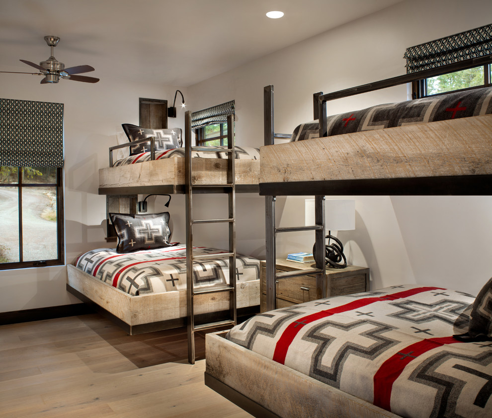 This is an example of a rustic gender neutral kids' bedroom in Other with white walls, light hardwood flooring and beige floors.