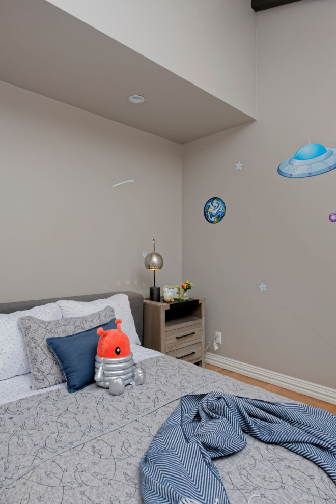 Diseño de dormitorio infantil actual de tamaño medio con paredes beige y suelo de madera en tonos medios