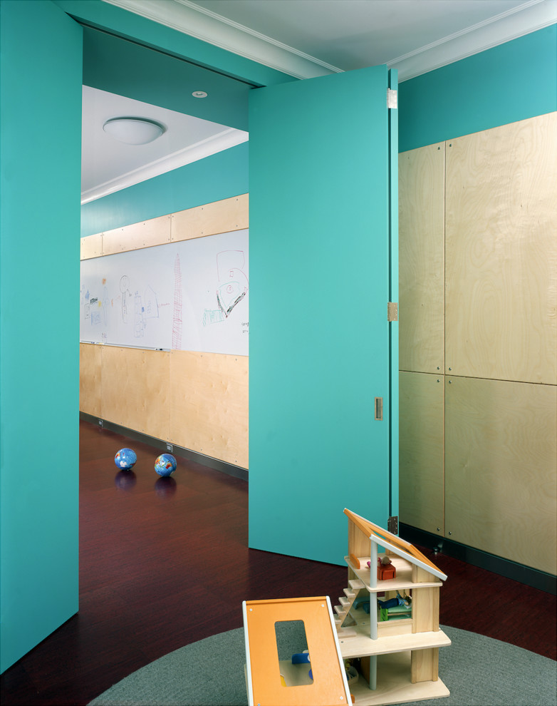 Cette image montre une grande chambre d'enfant minimaliste avec un mur multicolore et un sol en liège.
