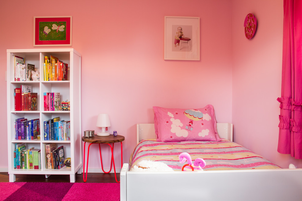 Ejemplo de dormitorio infantil de 4 a 10 años moderno de tamaño medio con paredes rosas y suelo de madera oscura