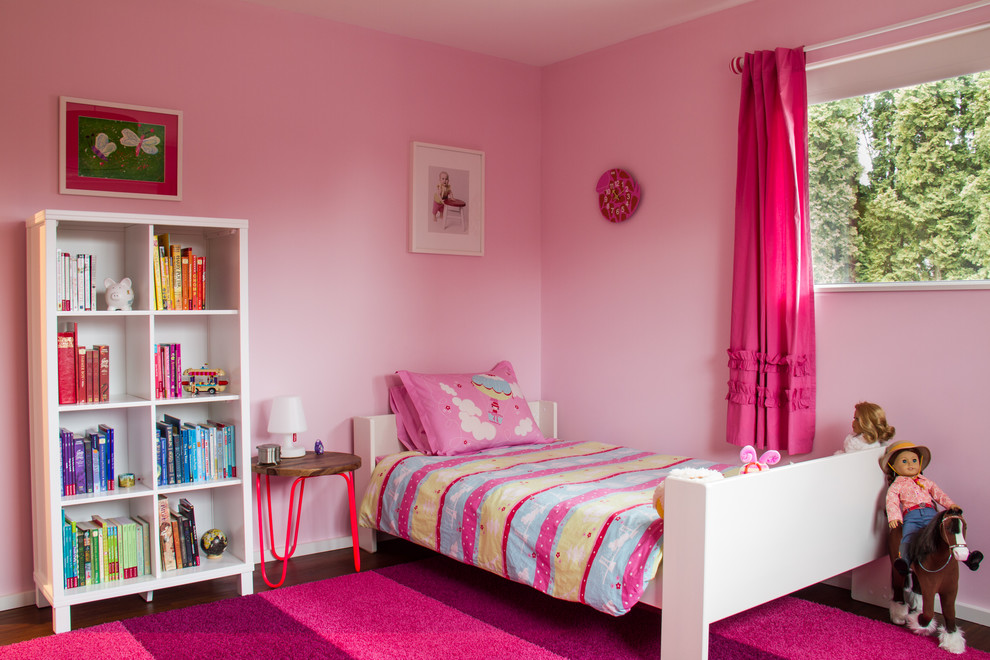 На фото: детская среднего размера в стиле модернизм с спальным местом, розовыми стенами и темным паркетным полом для ребенка от 4 до 10 лет, девочки