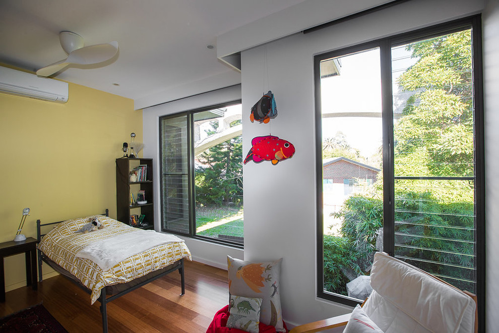 Foto de dormitorio infantil de 4 a 10 años minimalista de tamaño medio con suelo de madera clara y paredes amarillas