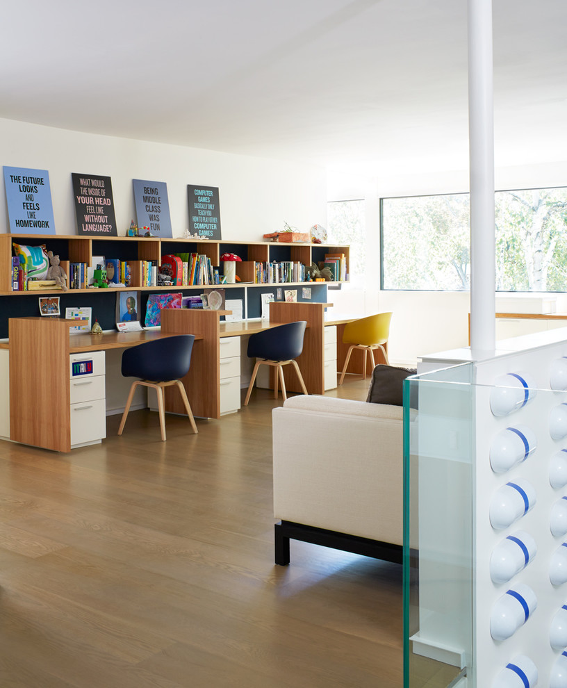 Imagen de habitación infantil unisex actual con paredes blancas, escritorio y suelo de madera clara