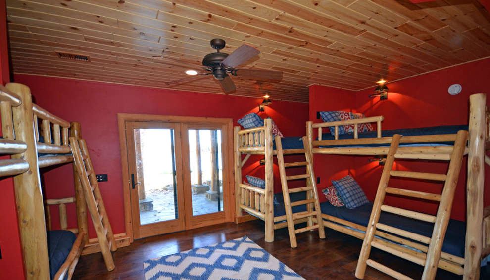Modelo de dormitorio infantil de 4 a 10 años rústico grande con paredes rojas, suelo de madera en tonos medios y suelo marrón