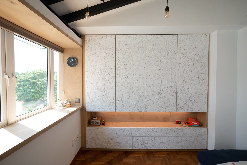 Esempio di una piccola cameretta per bambini da 1 a 3 anni design con pareti bianche, pavimento in legno massello medio e pavimento marrone