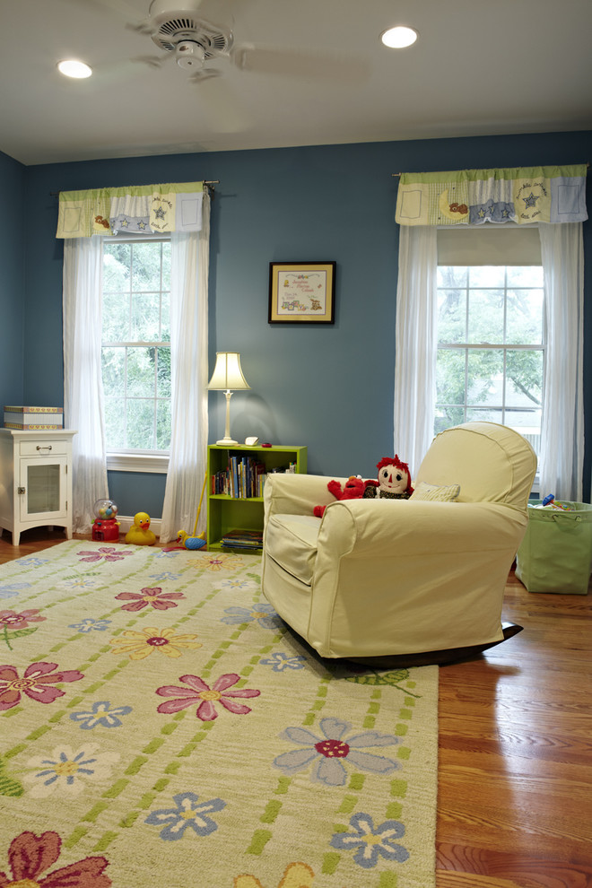 Modelo de dormitorio infantil de 1 a 3 años tradicional de tamaño medio con paredes azules y suelo de madera en tonos medios