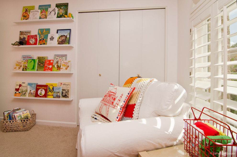 This is an example of a medium sized modern gender neutral toddler’s room in Phoenix with white walls and carpet.