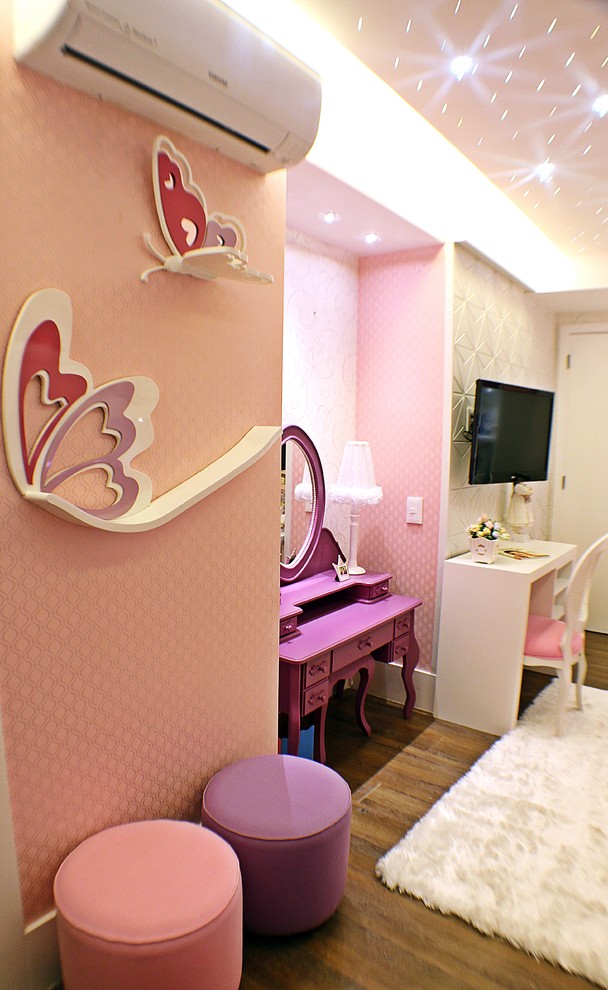 This is an example of a medium sized bohemian children’s room for girls in Other with pink walls and vinyl flooring.