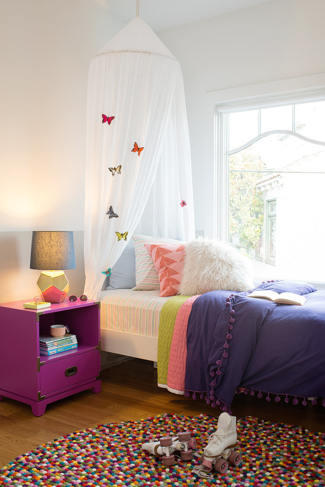Bild på ett mellanstort funkis flickrum kombinerat med sovrum, med vita väggar, ljust trägolv och brunt golv