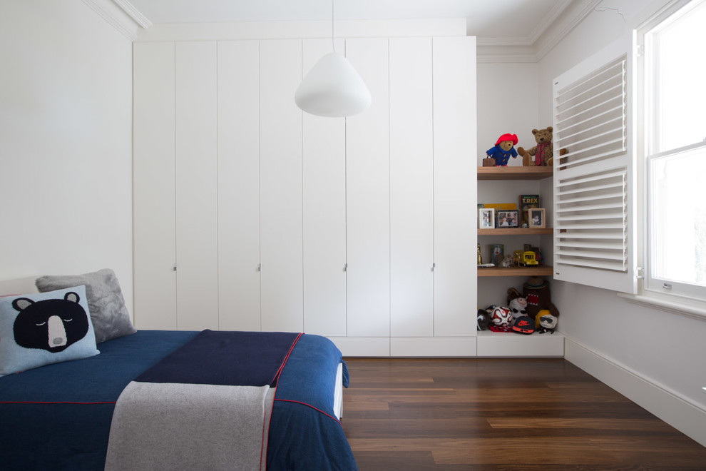 Modern inredning av ett pojkrum kombinerat med sovrum, med vita väggar och mörkt trägolv
