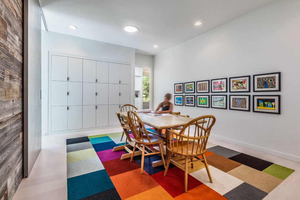 This is an example of a medium sized contemporary gender neutral kids' study space in Charleston with white walls and light hardwood flooring.