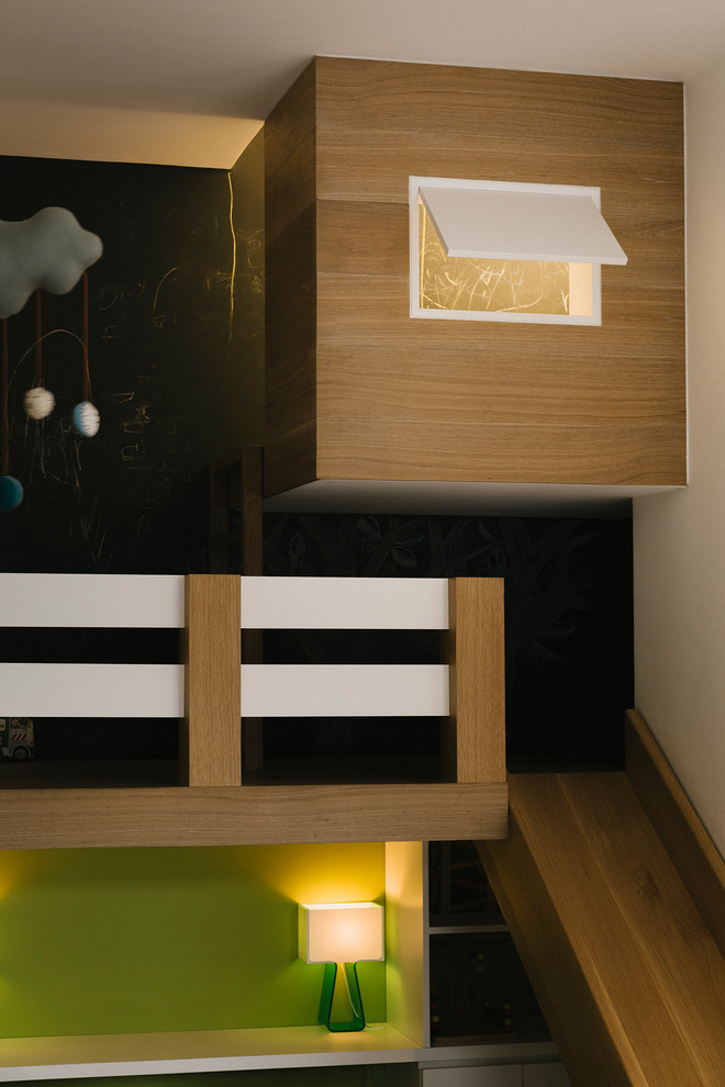 Photo of a large contemporary gender neutral playroom in New York with black walls and light hardwood flooring.