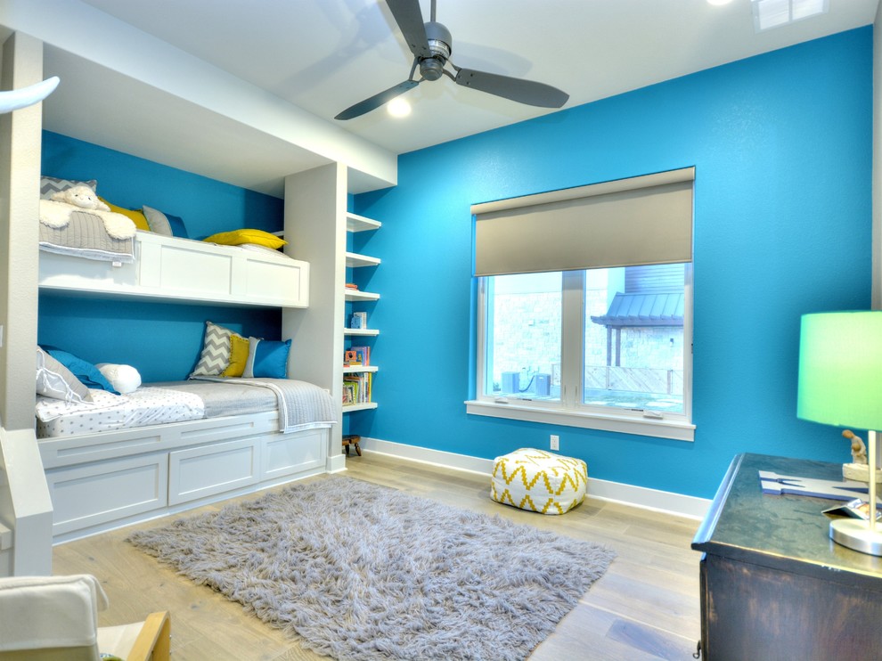 Immagine di una cameretta da letto contemporanea con pareti blu e pavimento in legno massello medio