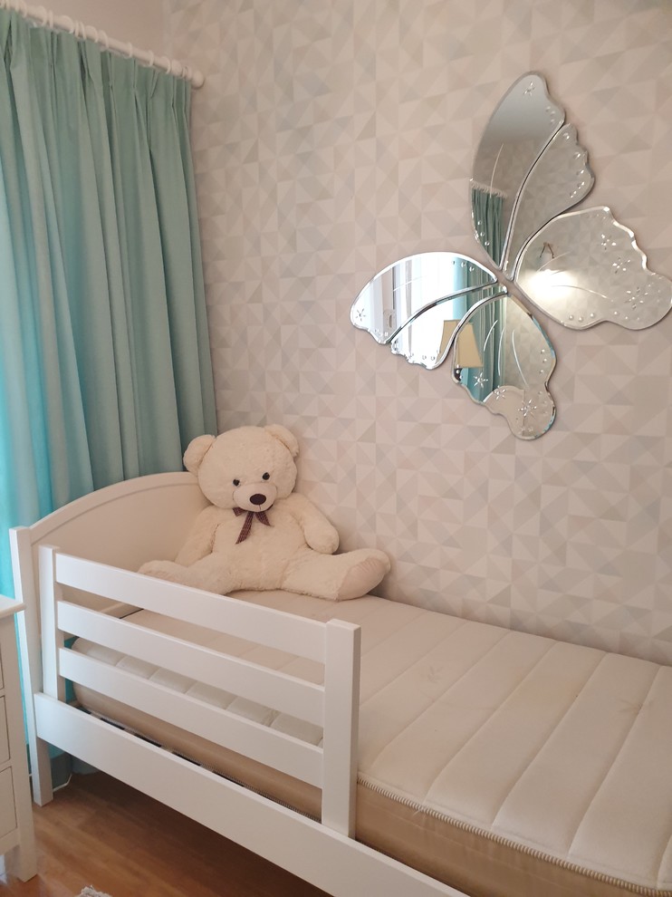 На фото: нейтральная детская среднего размера в стиле модернизм с спальным местом, розовыми стенами и полом из ламината для ребенка от 4 до 10 лет с