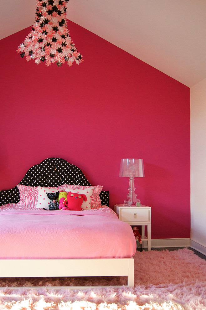 This is an example of a large classic toddler’s room for girls in New York with pink walls and dark hardwood flooring.