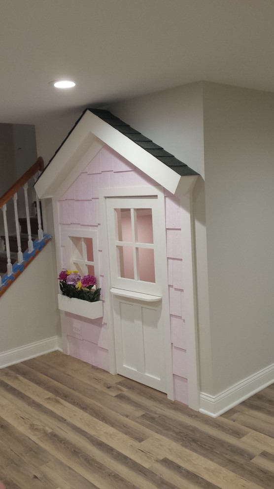 Foto på ett litet amerikanskt könsneutralt barnrum kombinerat med lekrum och för 4-10-åringar, med rosa väggar, laminatgolv och brunt golv