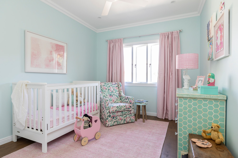 Modelo de habitación de bebé niña clásica renovada grande con paredes blancas, suelo de madera oscura y suelo marrón