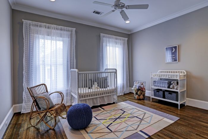 Ejemplo de habitación de bebé neutra de estilo americano grande con paredes grises y suelo de madera en tonos medios