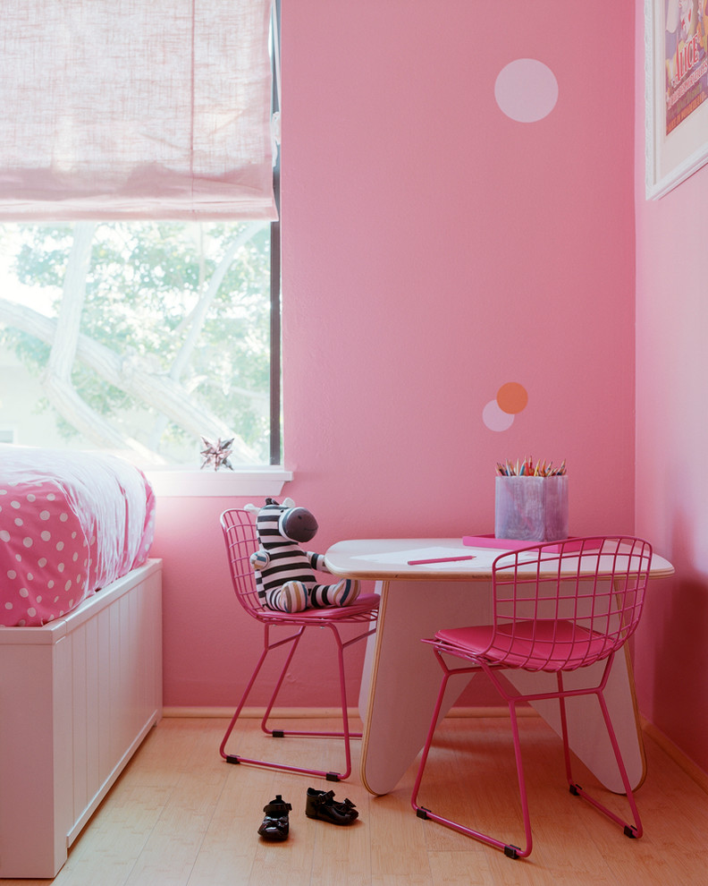 This is an example of a classic children’s room for girls in Los Angeles with pink walls and light hardwood flooring.