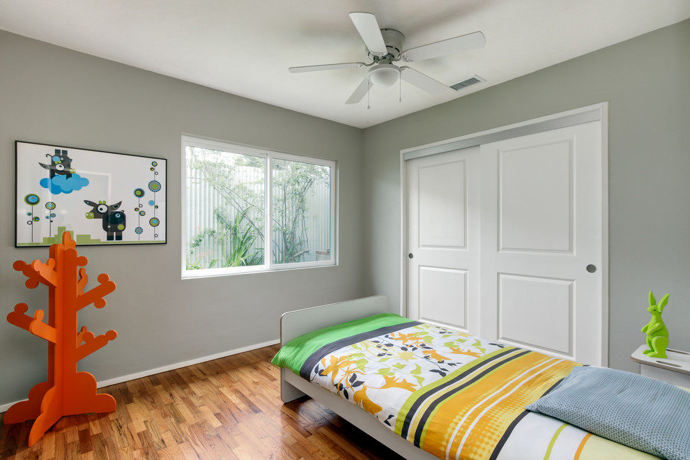 Imagen de dormitorio infantil de 4 a 10 años moderno de tamaño medio con paredes grises y suelo de madera en tonos medios