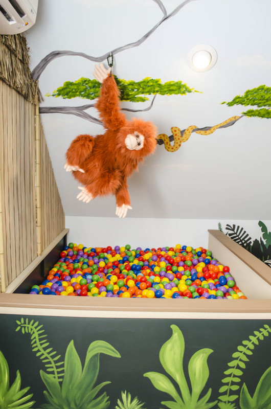 Ispirazione per una grande cameretta per bambini tropicale con pareti multicolore e pavimento in legno massello medio