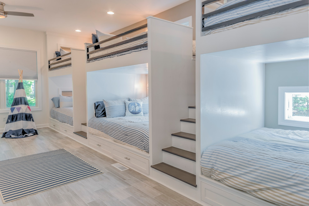 Diseño de dormitorio infantil de 4 a 10 años costero grande con suelo de madera clara y paredes blancas