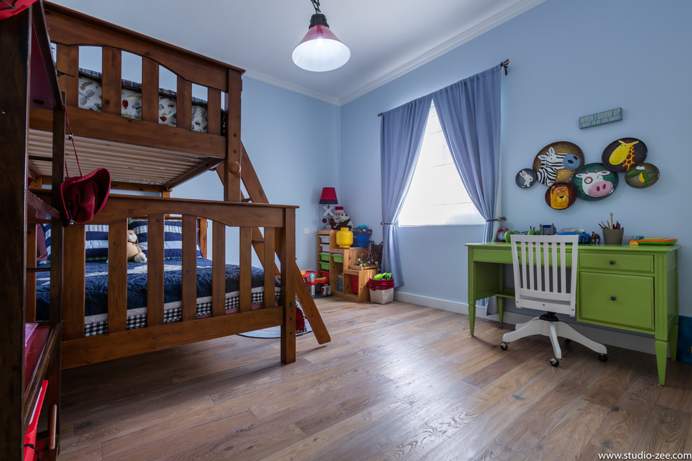 This is an example of a traditional children’s room for boys in Other with blue walls and light hardwood flooring.