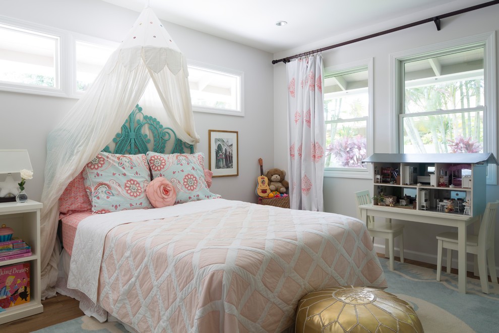 Photo of a classic children’s room for girls in Hawaii with white walls, medium hardwood flooring and brown floors.