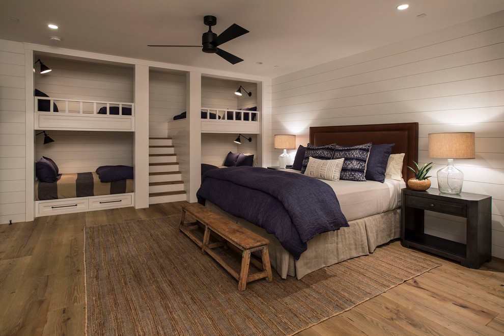 Aménagement d'une chambre neutre bord de mer avec un mur blanc, un sol en bois brun, un sol marron et un lit superposé.