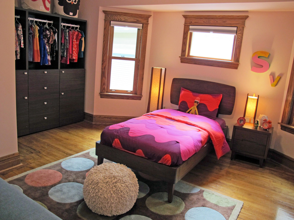Modelo de dormitorio infantil de 4 a 10 años moderno de tamaño medio con paredes rosas y suelo de madera en tonos medios