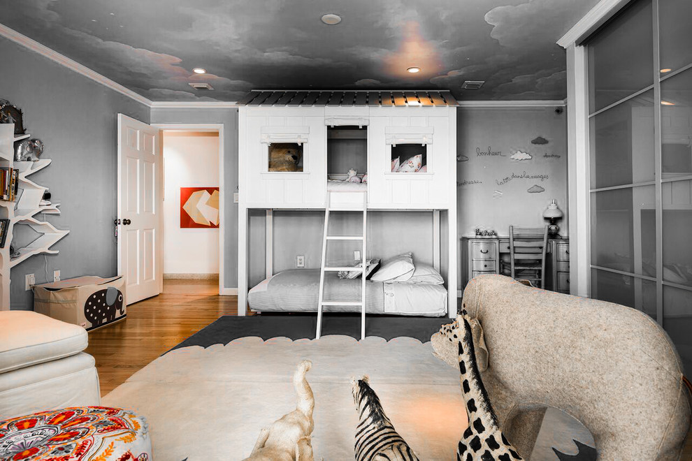 Modelo de dormitorio infantil de 4 a 10 años actual de tamaño medio con paredes azules y suelo de madera en tonos medios