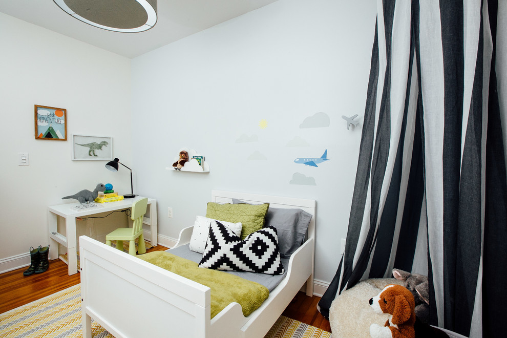 This is an example of a small contemporary toddler’s room for boys in New York with grey walls, dark hardwood flooring and brown floors.