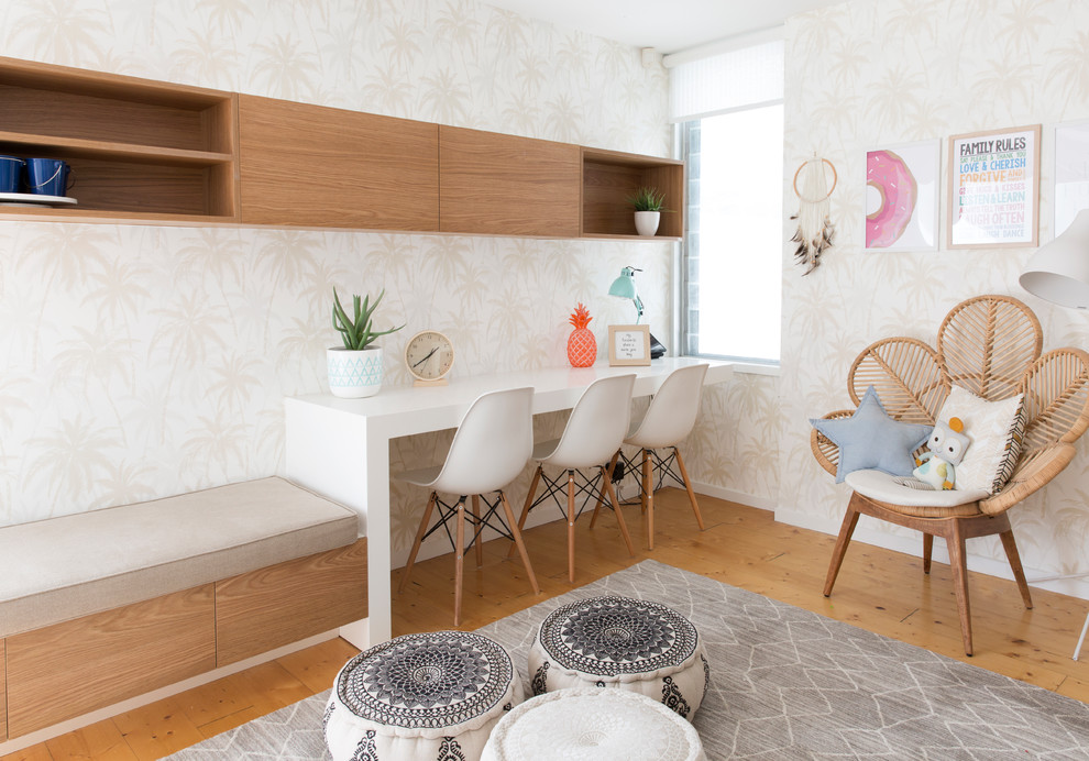 Inredning av ett modernt stort könsneutralt tonårsrum kombinerat med skrivbord, med beige väggar, mellanmörkt trägolv och beiget golv