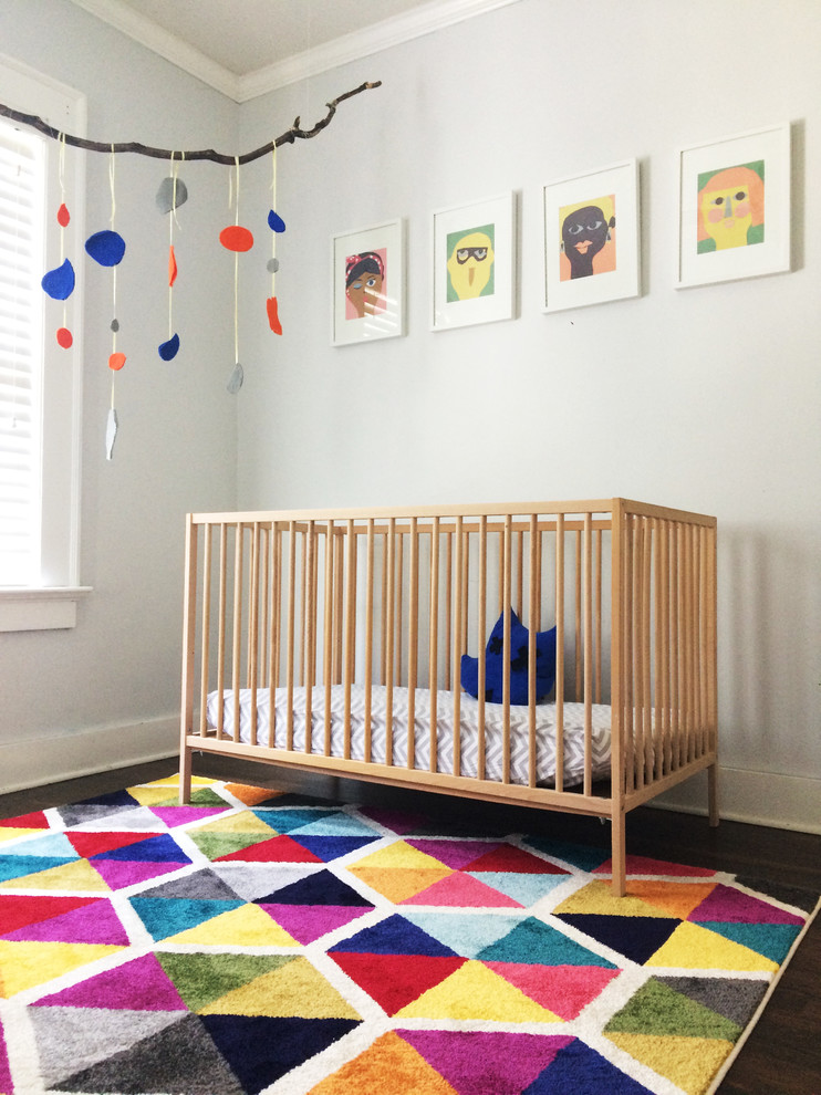 Eklektisk inredning av ett litet könsneutralt småbarnsrum kombinerat med sovrum, med grå väggar, mellanmörkt trägolv och flerfärgat golv
