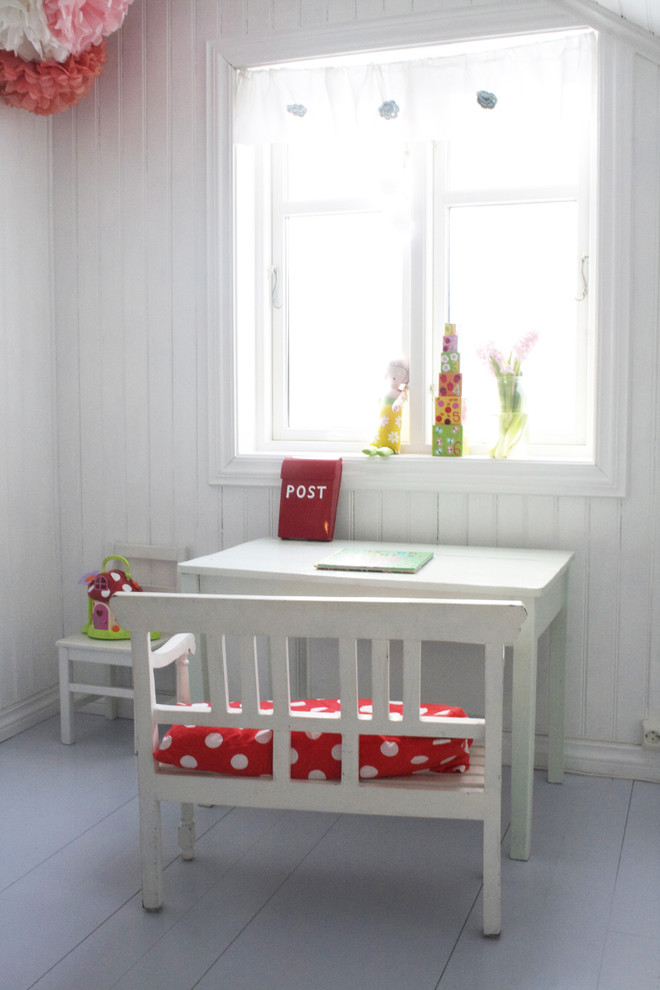 Minimalistisk inredning av ett könsneutralt småbarnsrum kombinerat med skrivbord, med vita väggar, målat trägolv och grått golv