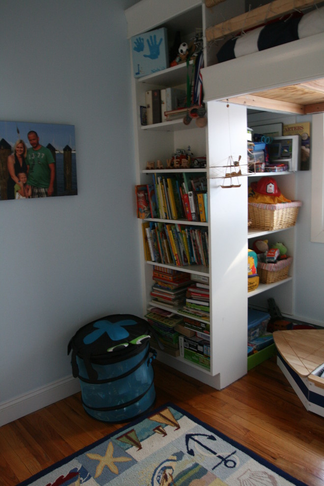 Immagine di una piccola cameretta per bambini stile marinaro con pareti blu e pavimento in legno massello medio