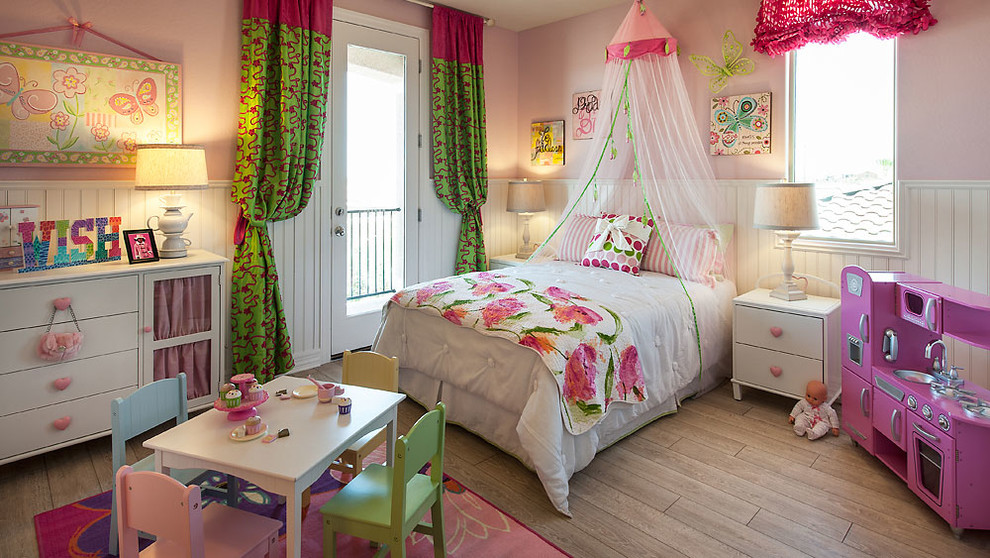 Esempio di una cameretta per bambini da 4 a 10 anni boho chic di medie dimensioni con pareti rosa e pavimento in legno massello medio