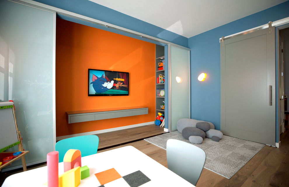 Exempel på ett modernt könsneutralt barnrum kombinerat med lekrum, med blå väggar, mörkt trägolv och brunt golv