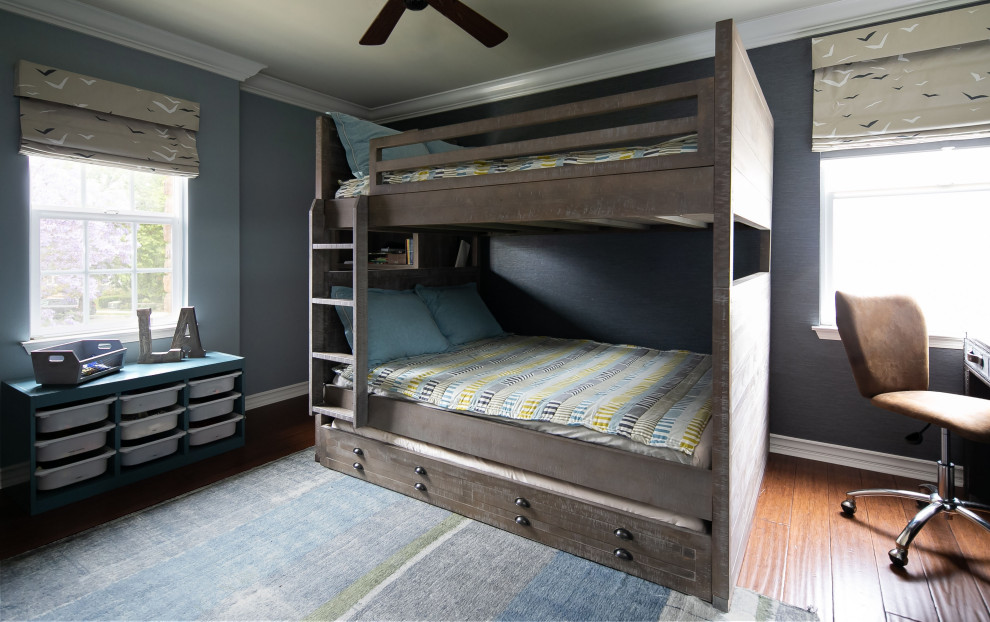 Immagine di una cameretta per bambini classica di medie dimensioni con pareti blu, pavimento in legno massello medio, pavimento marrone e carta da parati