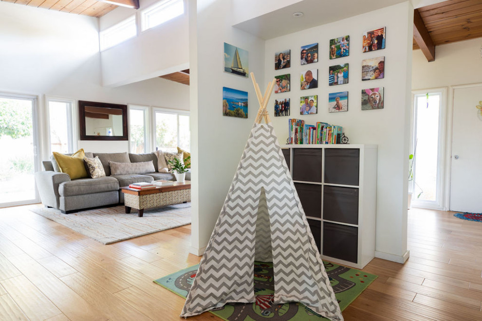 Ispirazione per una cameretta per bambini da 4 a 10 anni moderna di medie dimensioni con pareti bianche, pavimento in legno massello medio e pavimento marrone