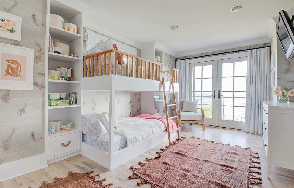 This is an example of a large beach style kids' bedroom for girls in Other with light hardwood flooring, wallpapered walls, multi-coloured walls and beige floors.